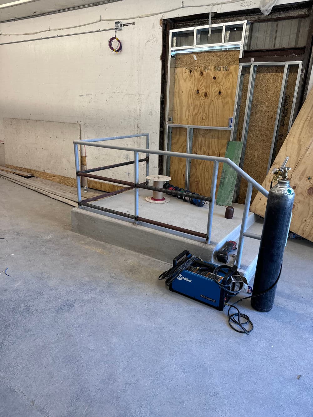 Metal ramp for accessibility in a workshop with tools and equipment nearby.