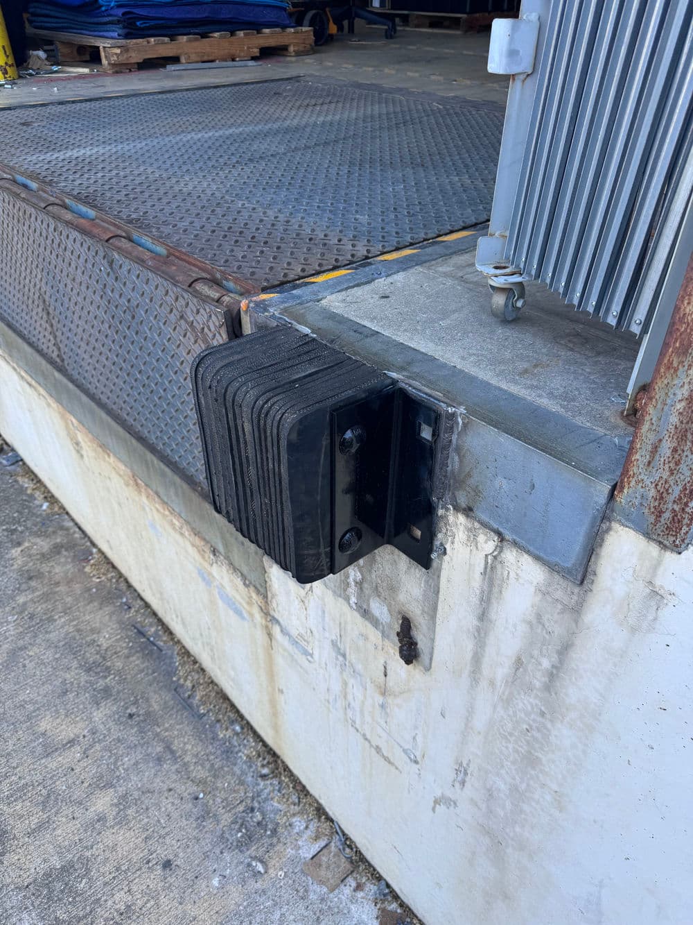 Rubber dock bumper installed on loading dock to protect against vehicle impact.
