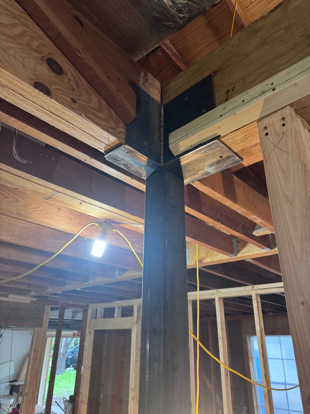 Steel beam installation in residential construction, showing structural support and wiring.