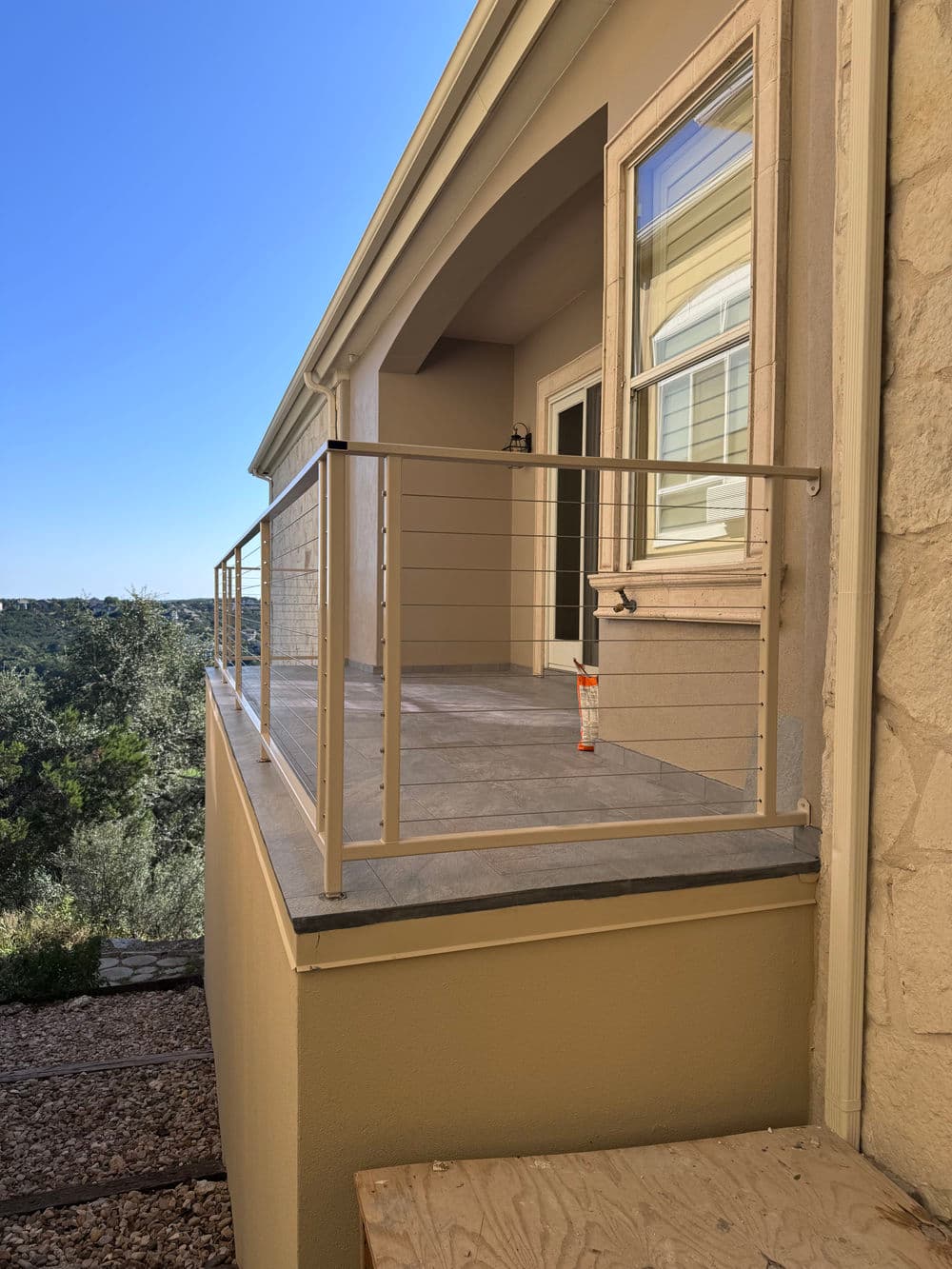 Modern balcony railing with scenic view in sunlight, featuring stone and concrete design.