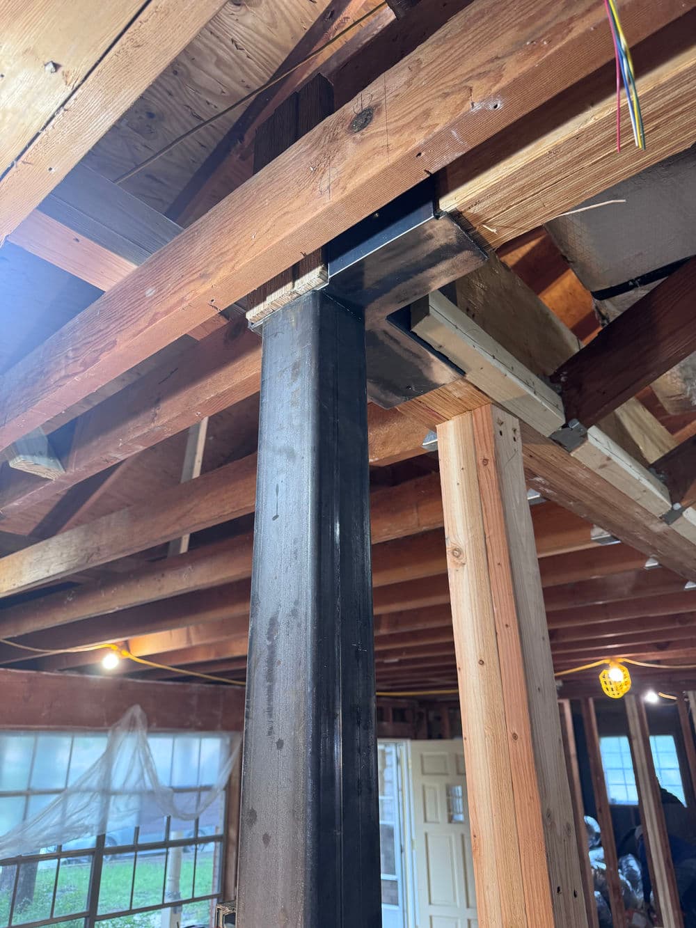 Steel support beam in a residential renovation, highlighting wooden framework and construction details.
