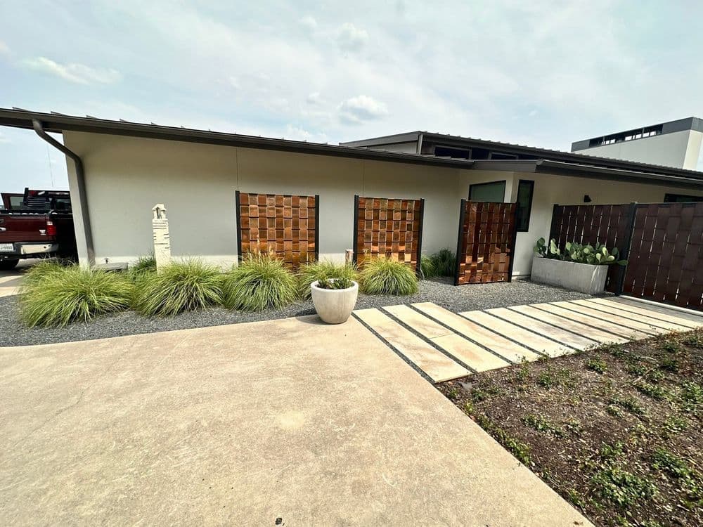Modern home exterior featuring wooden doors, stone pathway, and landscaped garden.