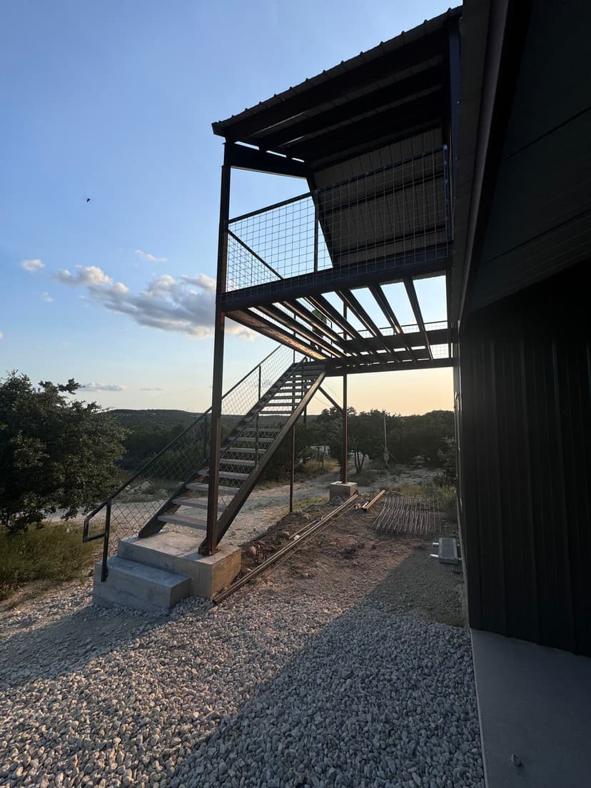 Modern outdoor staircase with metal railing beside a contemporary building, sunset background.